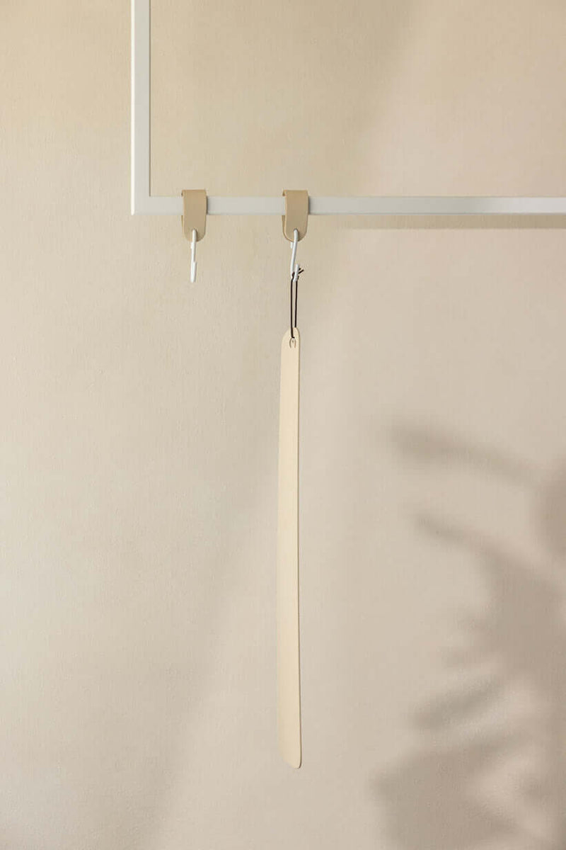 Schuhlöffel TILO aus high-quality metall an einem minimalistischen Haken in modernm Interior.