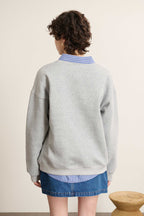 Vue arrière du sweat ample coloris gris, coupe droite avec base et poignets en bord-côtes élastiqué ton sur ton.