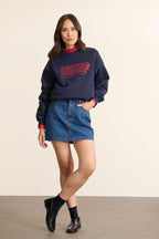 Mannequin femme de face portant un sweat ample coloris marine, col rond, manches longues et imprimé sur le devant.
