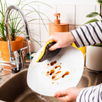 Eponge lavable jaune nettoyant une assiette