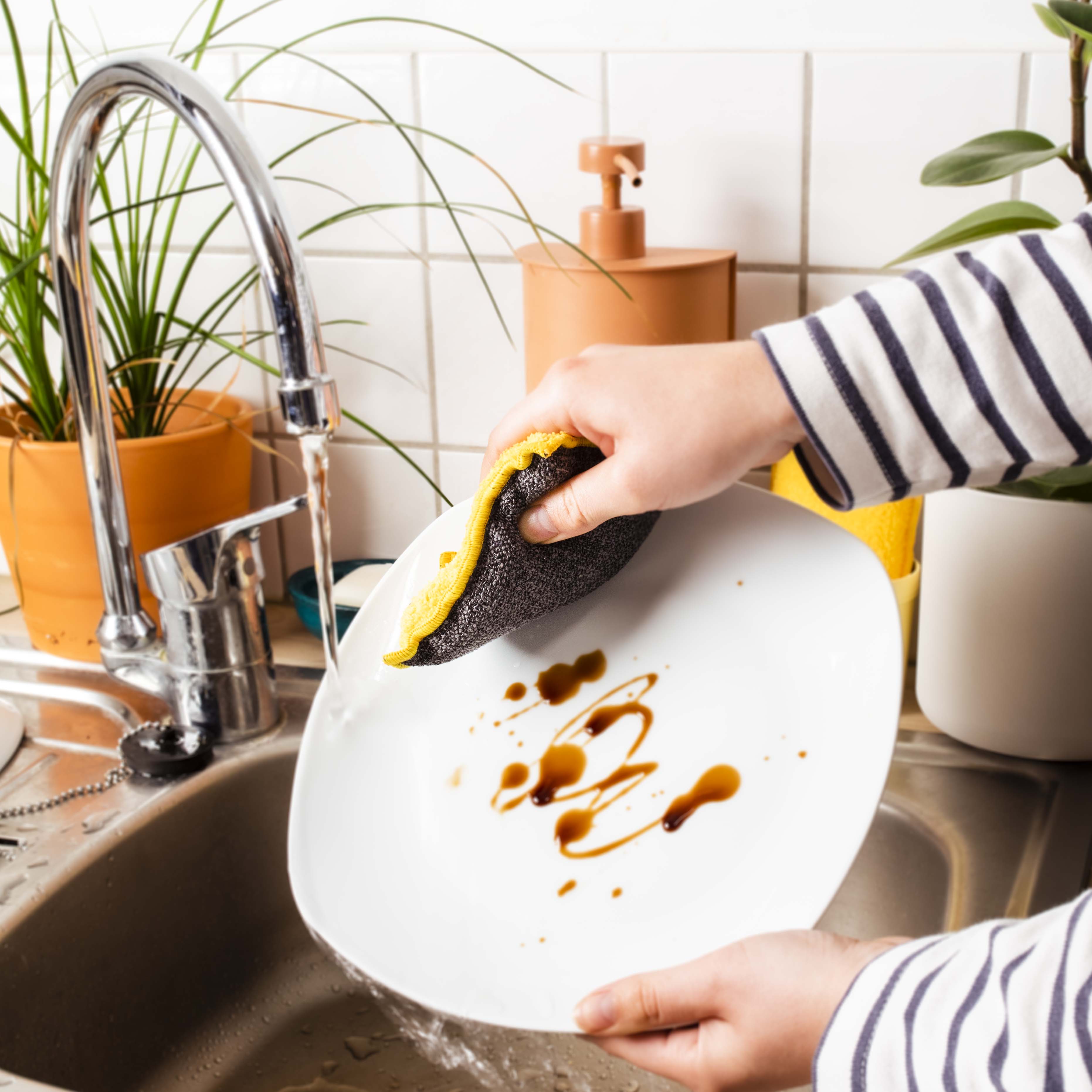 Eponge lavable jaune nettoyant une assiette