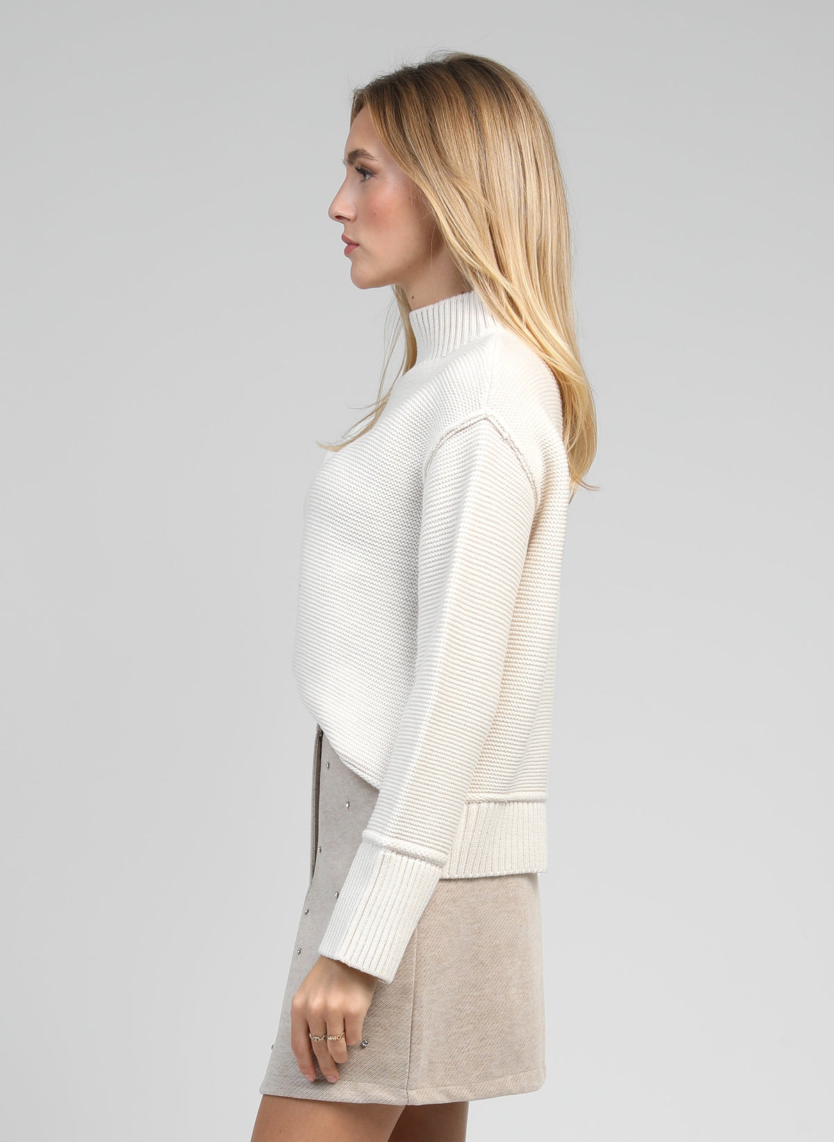 An'ge – Pull Valora Ecru, mannequin portant un pull blanc cassé à col montant, vue de profil