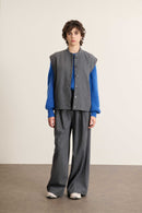 Mannequin femme de face portant une veste sans manches grise à rayures, coupe droite avec col rond et poches plaquées.