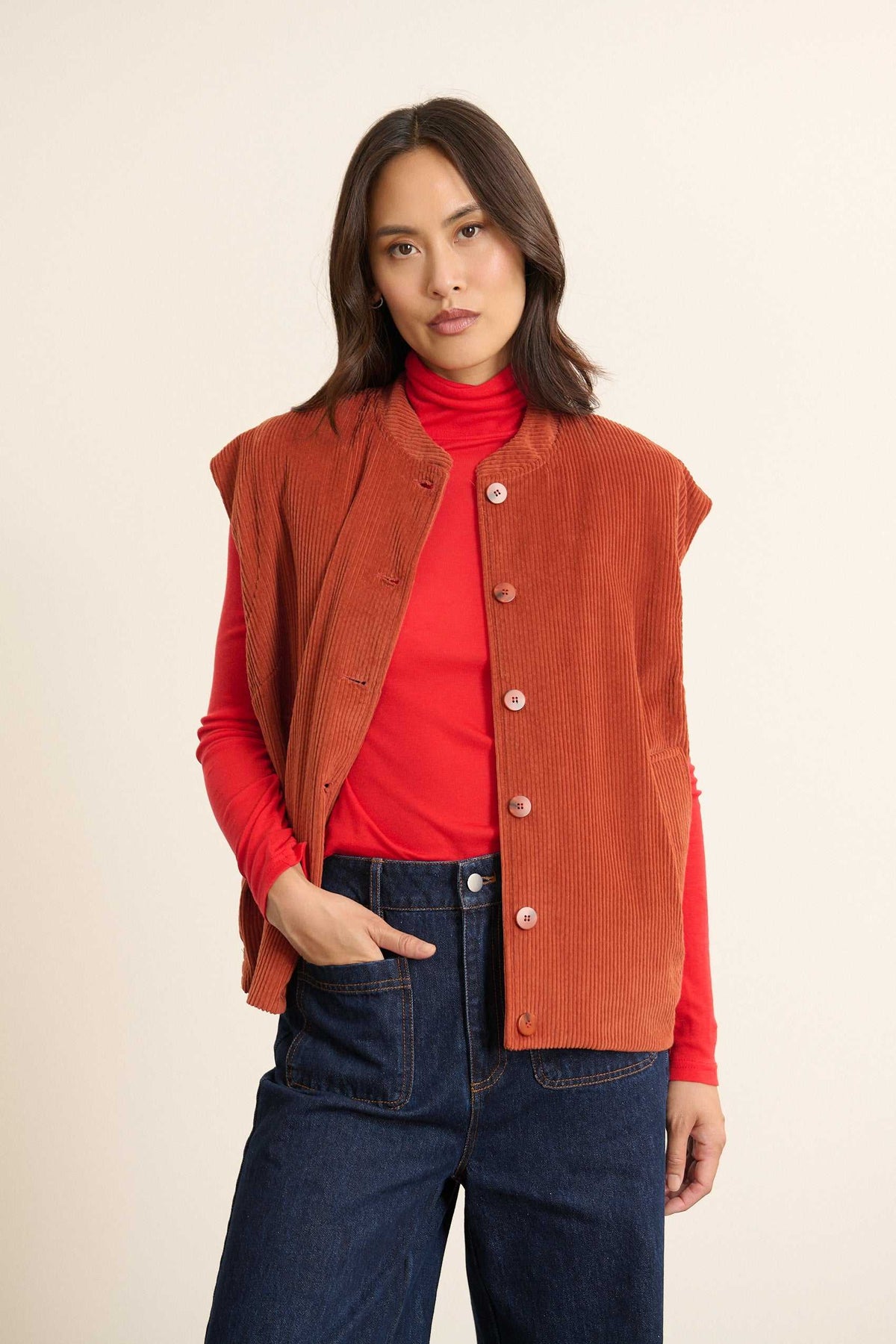 Mannequin femme de face portant une veste sans manches matelassée en velours terre cuite, coupe droite et col rond classique.