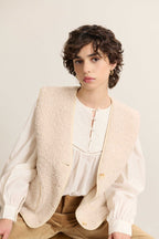 Chaqueta sin mangas efecto borreguito color crudo, colección otoño invierno 2025 de Garance Paris, botón de asta y bolsillos de parche. 