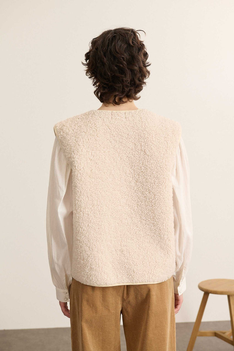 Vue arrière de la veste sans manches, coupe droite avec finitions nettes et encolure arrondie bordée proprement.