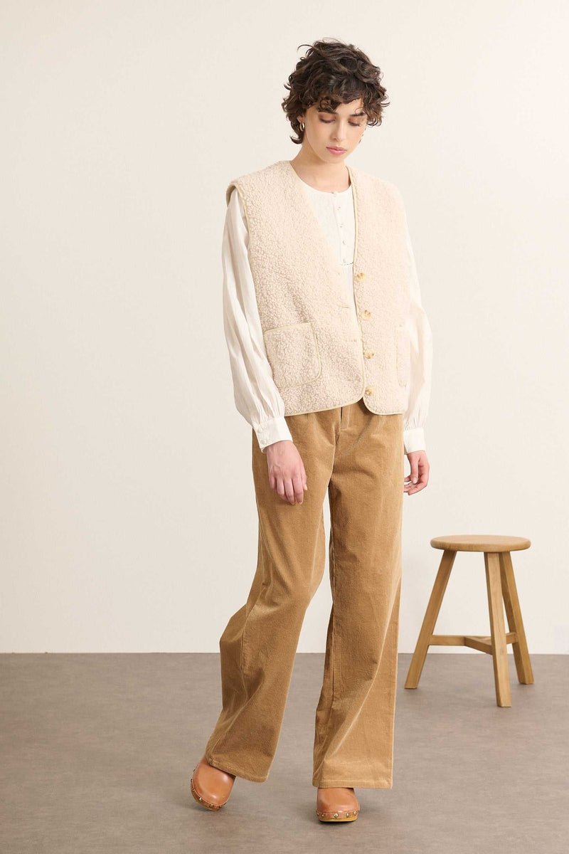 Veste écrue en fausse peau de mouton, matière chaude et légère adaptée aux superpositions de mi-saison. 