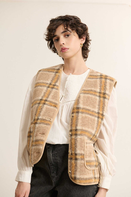 Bouton effet corne en contraste, cousu au bord de la patte centrale avec couture apparente sur la veste POLA sans manches.