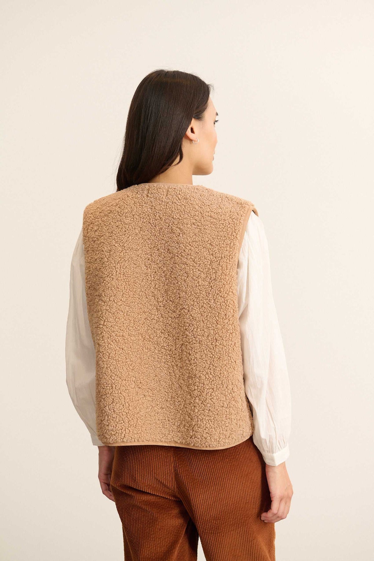 Veste sans manches beige effet peau de mouton, collection Garance automne hiver 2025, fermeture brandebourg sur le devant.