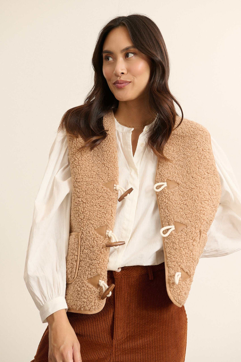 Fabriquée entièrement en polyester, veste sans manches POLETTE coloris beige avec bouton brandebourg.