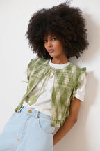 Veste estivale kaki sans manches en tissu ikat, lien et pompons au col, finitions volantées