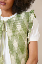 Veste kaki bohème sans manches en tissu ikat, volants élégants et col avec lien à pompons
