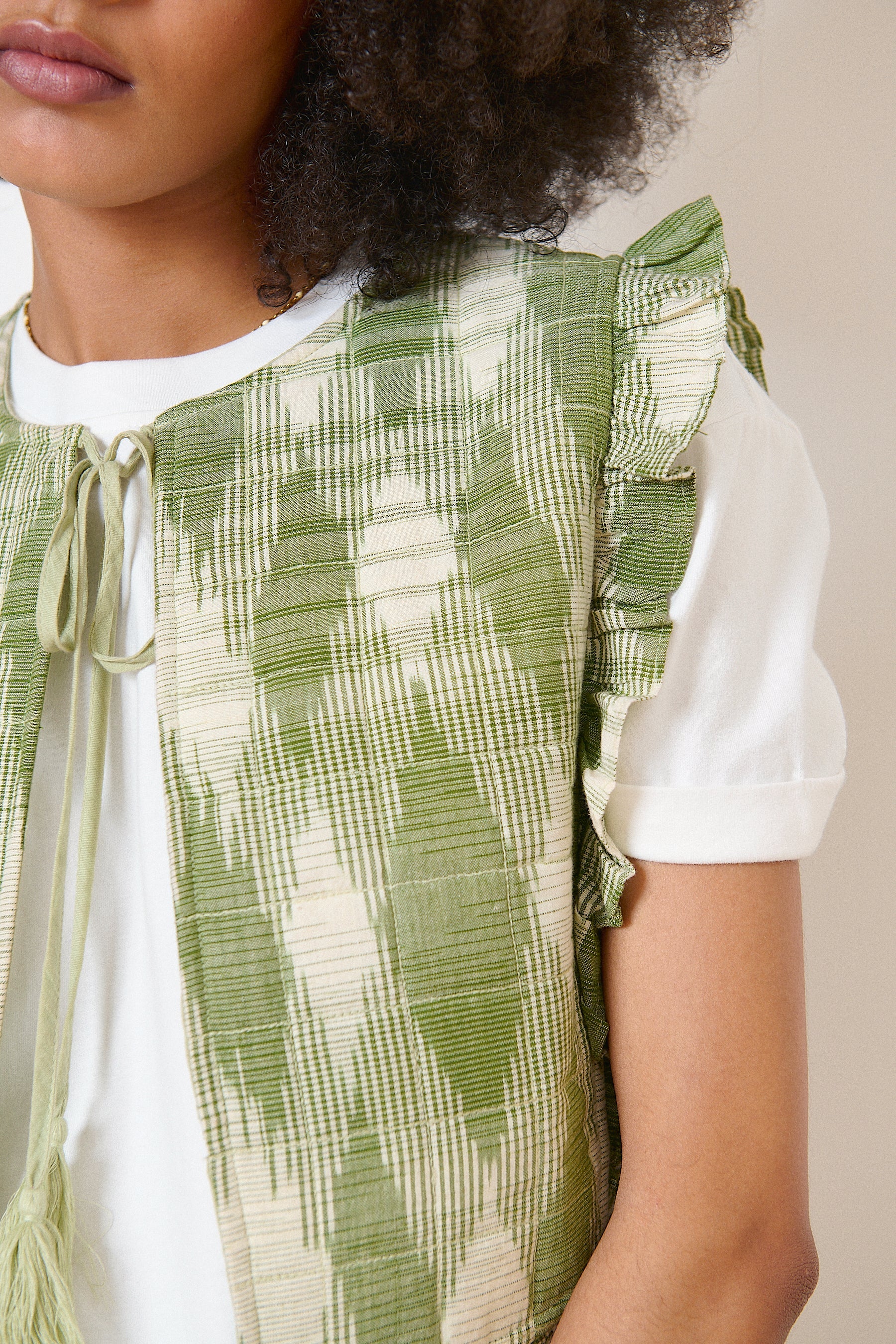 Veste kaki bohème sans manches en tissu ikat, volants élégants et col avec lien à pompons
