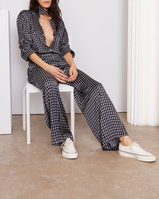 Officine Générale – Chemise Elzi - Bleu Marine/Écru - Femme, mannequin assise de face, portant un ensemble pantalon et chemise noirs et blancs