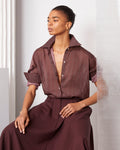 Officine Générale – Chemise Augustine - Lie De Vin/Bordeaux/Écru - Femme, mannequin assise portant une chemise à motifs et un pantalon marron