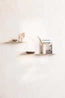 Modernes Wandregal LENN aus Metall mit dekorativen Objekten und einem Magazin an der Wand.