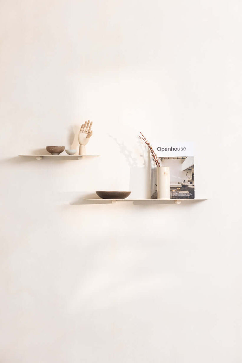 Modernes Wandregal LENN aus Metall mit dekorativen Objekten und einem Magazin an der Wand.