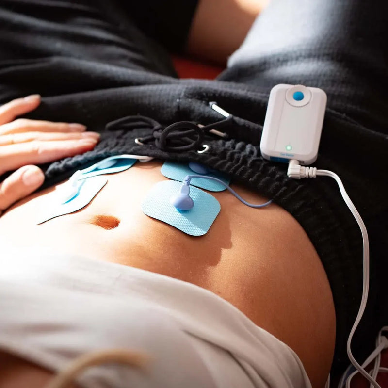 bluetens appareil électrostimulation qui apaise, soulage douleurs menstruelles et endométriose. Photo d'une femme allongée avec son appareil bluetens sur le bas ventre sous son pantalon 