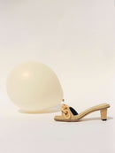 Catena Natural Mid-Heel Sandal in linen with raffia design beside a golden balloon, perfect for chic summer styles.