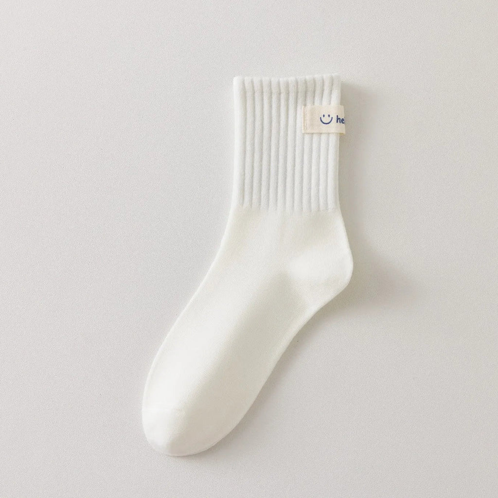 Chaussettes blanches montantes avec smiley, confortables et stylées, idéales avec des baskets. Coton épais, look tendance et maintien optimal.