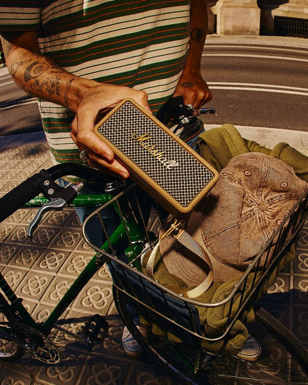 Marshall – Emberton III - Portable Speaker - Brown, a person holds a portable speaker above a bicycle basket