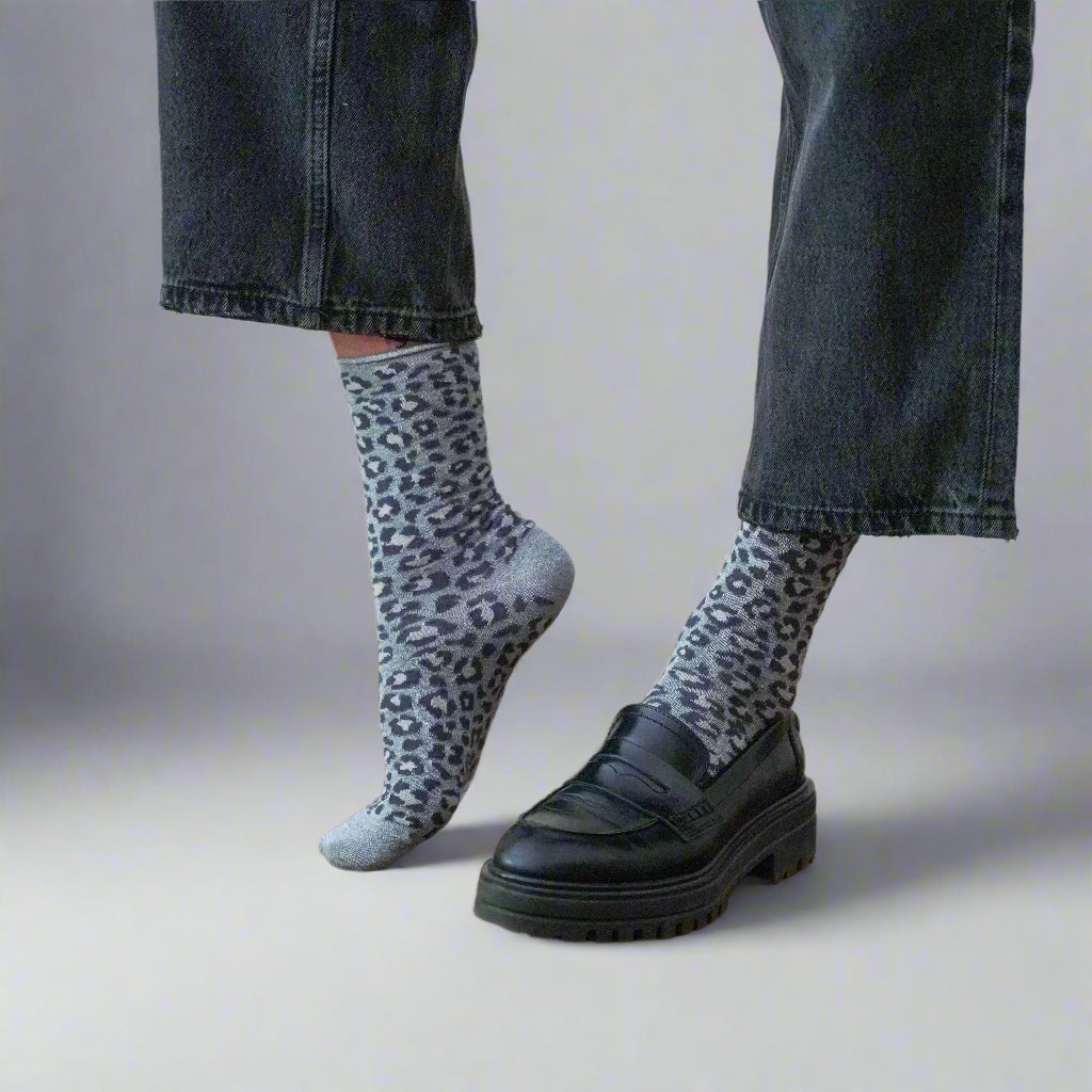 Calzini KLUE ecologici con motivo leopardato grigio abbinati a jeans e scarpe nere in pelle