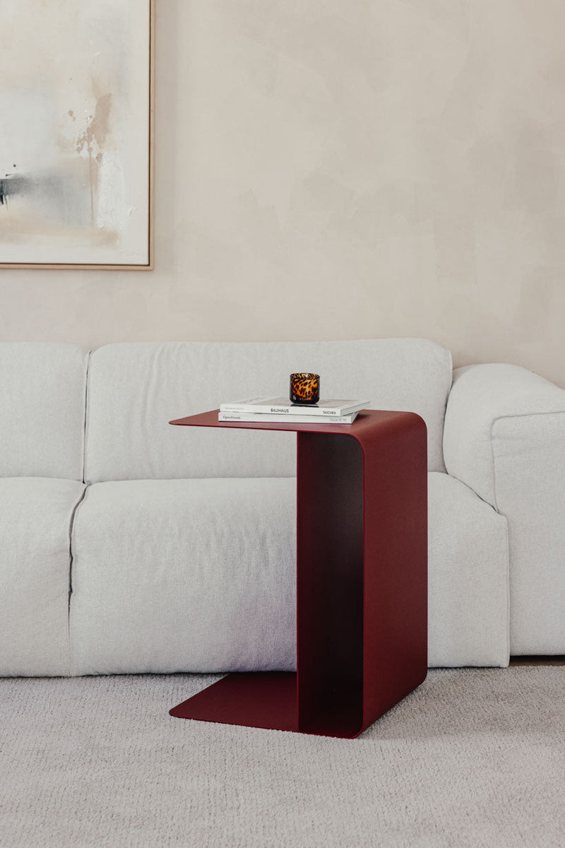 Beistelltisch COSMO aus pulverbeschichtetem Metall neben einem weißen Sofa mit Buch und Kerze.