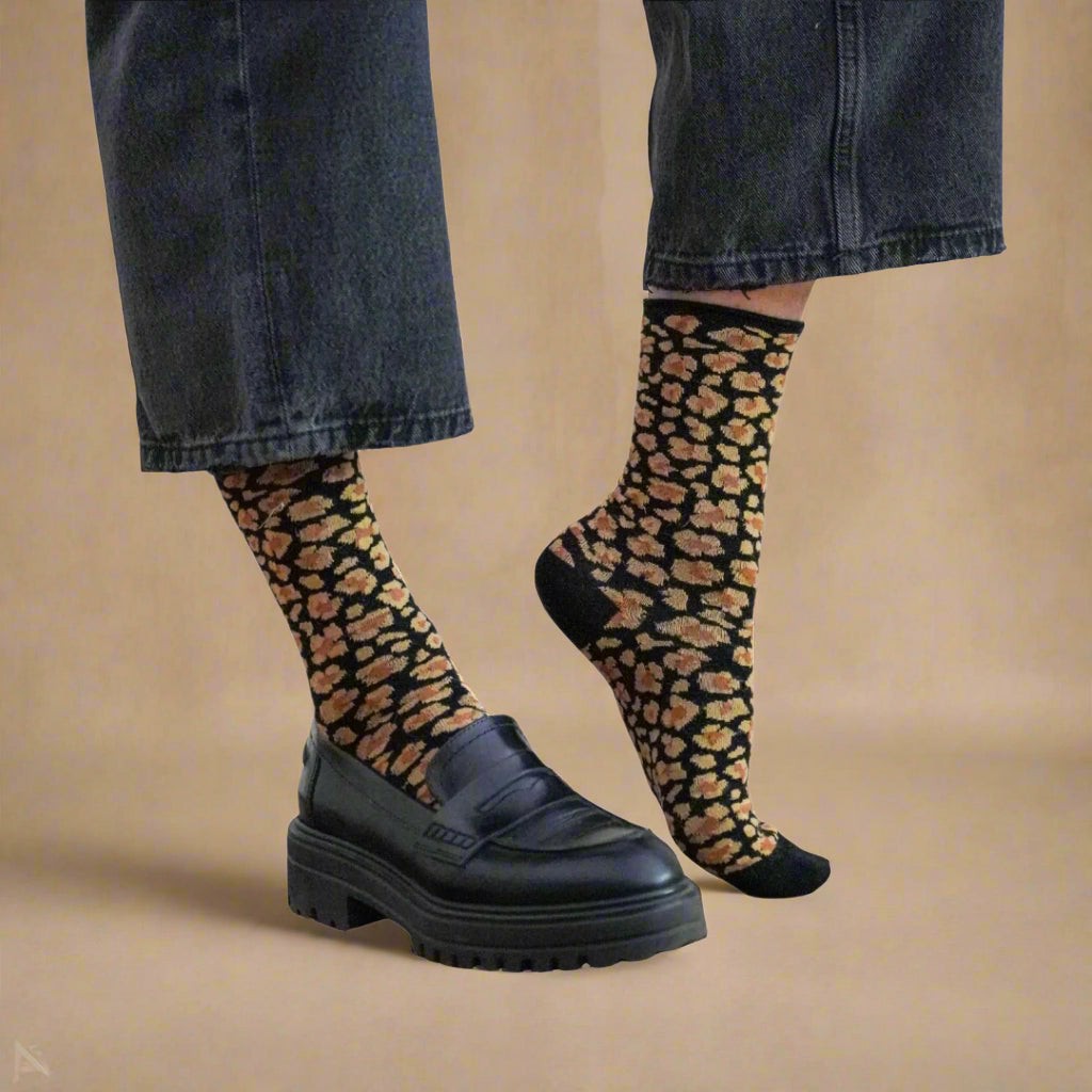 Calcetines KLUE de leopardo en tonos ámbar, respetuosos con el medioambiente, combinados con vaqueros y zapatos de piel negros