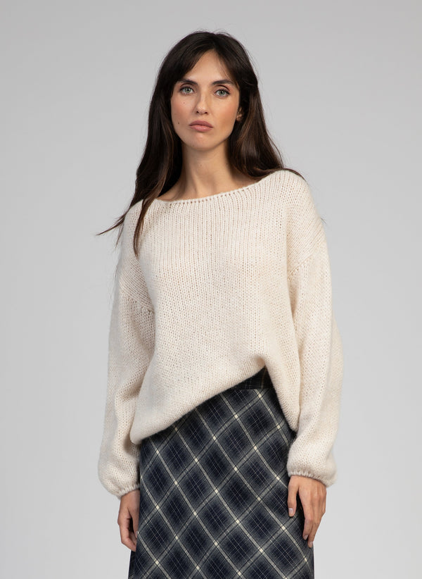 An'ge – Pull Labonita Ecru, modelka ubrana w beżowy dzianinowy sweter i spódnicę w kratę