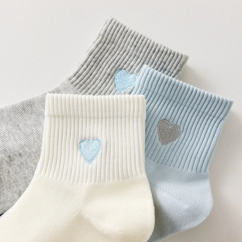 Lot de 3 chaussettes mi-hautes femme avec cœur bleu brodé. Coloris doux : gris, blanc cassé, bleu ciel. Bord côtelé. Confort et style au quotidien.