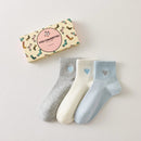 Lot de 3 chaussettes mi-hautes femme avec cœur bleu brodé. Coloris doux : gris, blanc cassé, bleu ciel. Bord côtelé. Confort et style au quotidien.