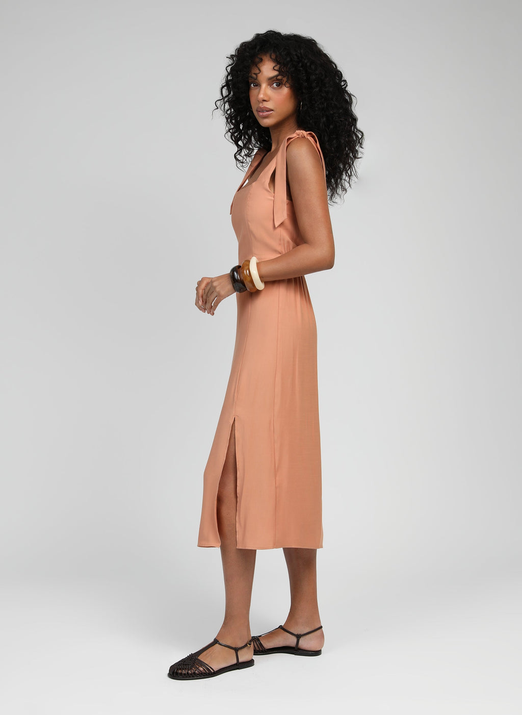 An'ge – Robe Midi Manta Terracotta, mannequin de profil portant une robe midi couleur pêche avec des sandales