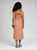 An'ge – Robe Midi Manta Terracotta, mannequin de dos portant une robe longue couleur pêche avec des sandales