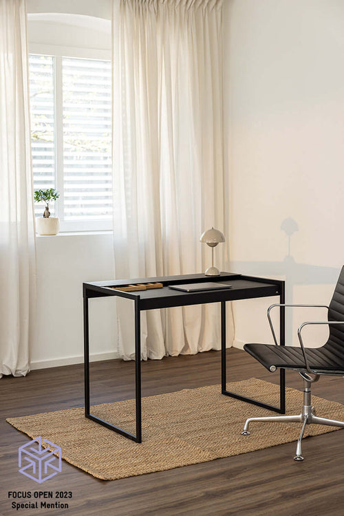 Schreibtisch DONNA in modernem Raum mit Stuhl und Teppich, minimalistisches Design in Schwarz.