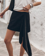 Woman wearing a black wrap skirt with a white t-shirt against a light background.