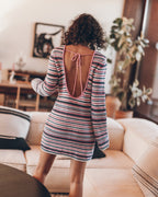 Woman wearing a striped dress with an open back in a living room.