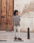 Woman standing on a street wearing a striped linen t-shirt, light jeans, and black leather sandals.