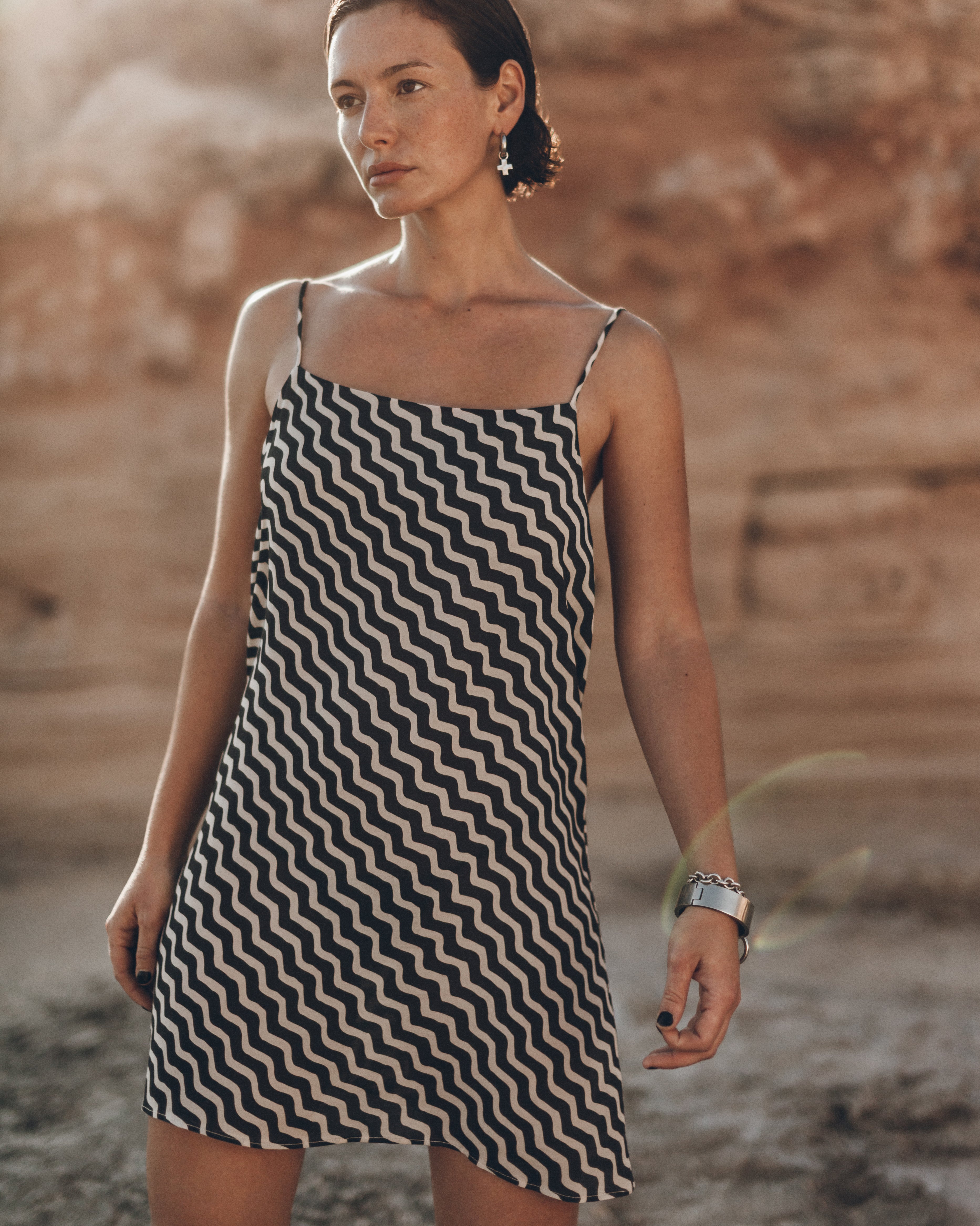 Woman wearing a black and white zigzag dress standing against a natural background
