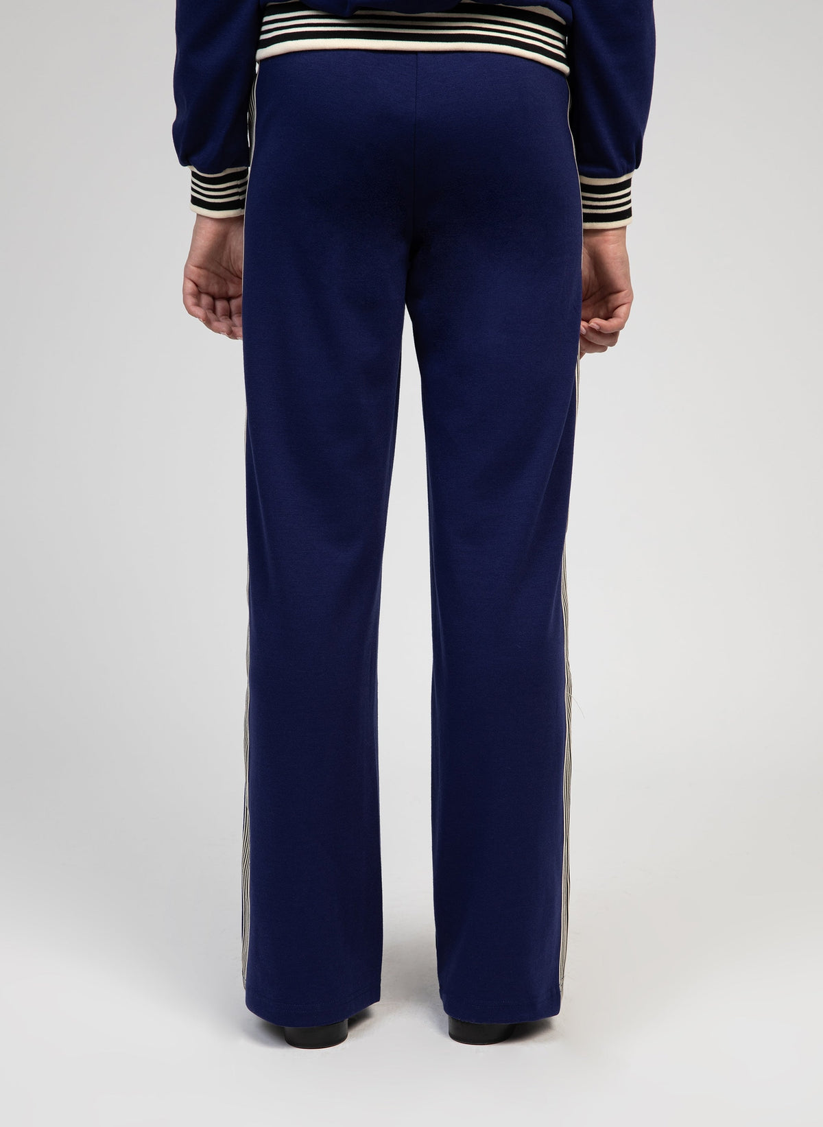 An'ge – Hose Patrivy Blau, marineblaue Jogginghose mit Seitenstreifen, von einem Model von hinten getragen