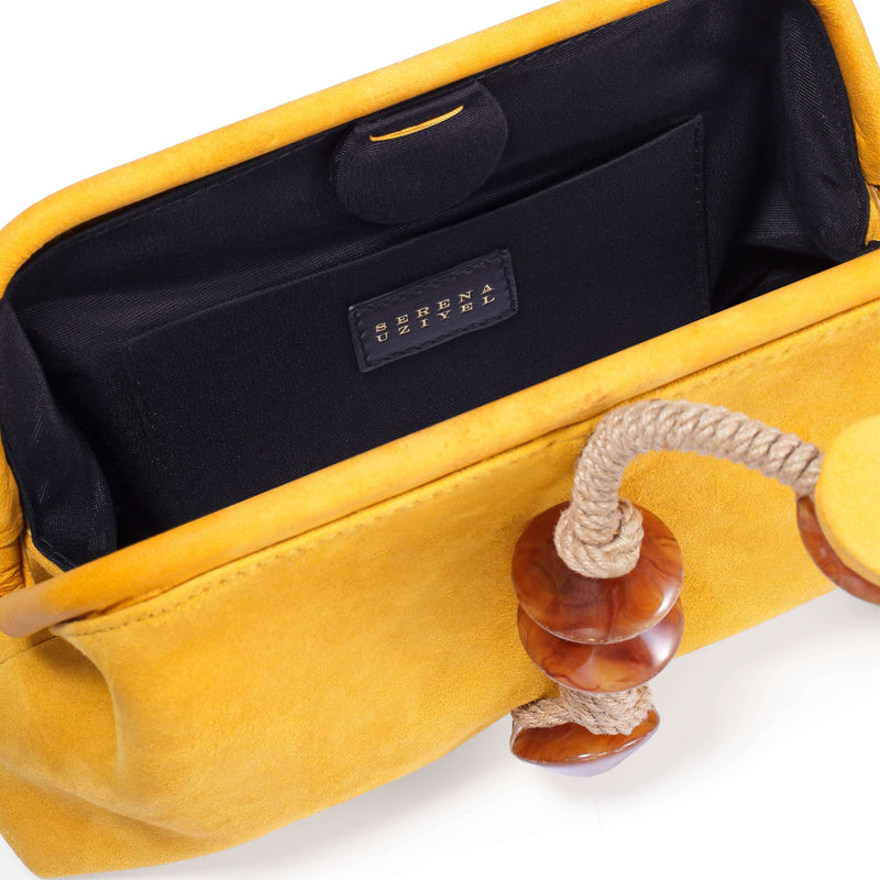 Interior view of the Petra Mustard Pouch Bag showcasing the soft suede material and unique wooden accents.