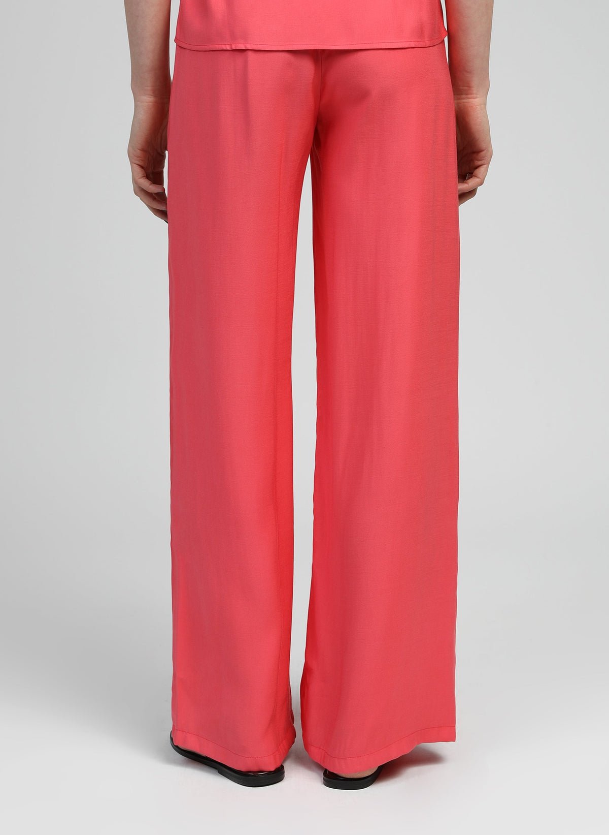 An'ge – Pantalon Phoebila Corail, pantalon large corail porté de dos par un mannequin
