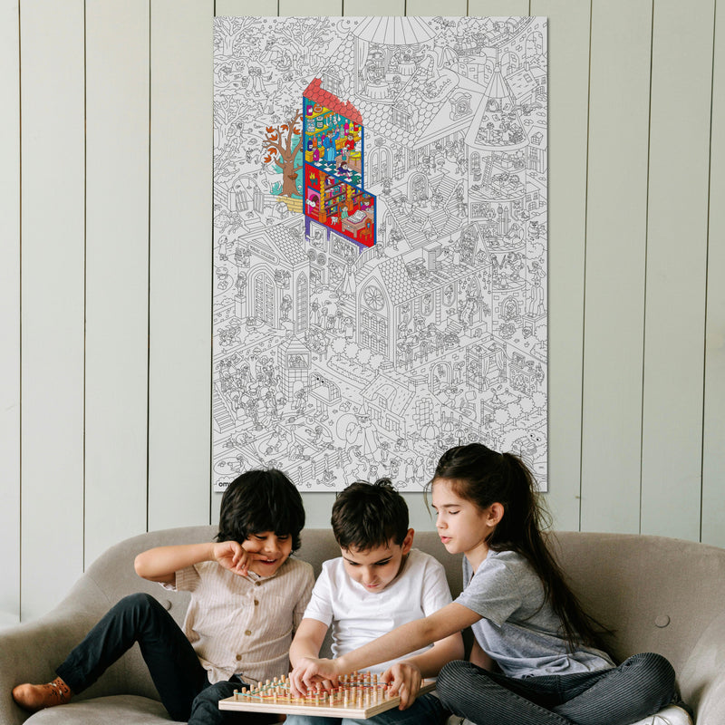 Trois enfants jouant devant le poster géant à colorier Magic College d’OMY affiché sur un mur – idéal pour décorer et animer une chambre avec créativité.