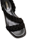 Ronda Black Flat Asymmetric Sandal featuring braided black straps and a sleek leather sole, perfect for summer wear.