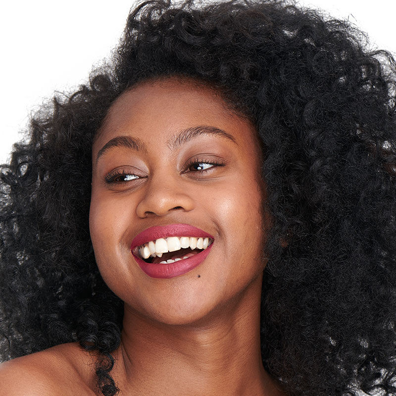 Tono granate de la barra de labios natural y limpia Pomponne en pieles oscuras.