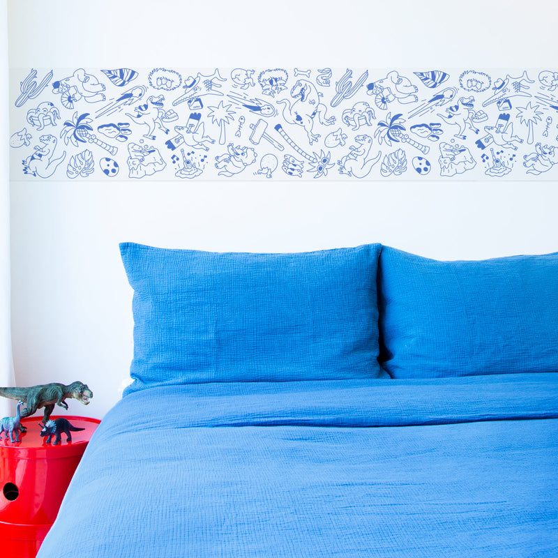 Décoration murale au-dessus d’un lit avec le motif dinosaures du rouleau adhésif OMY