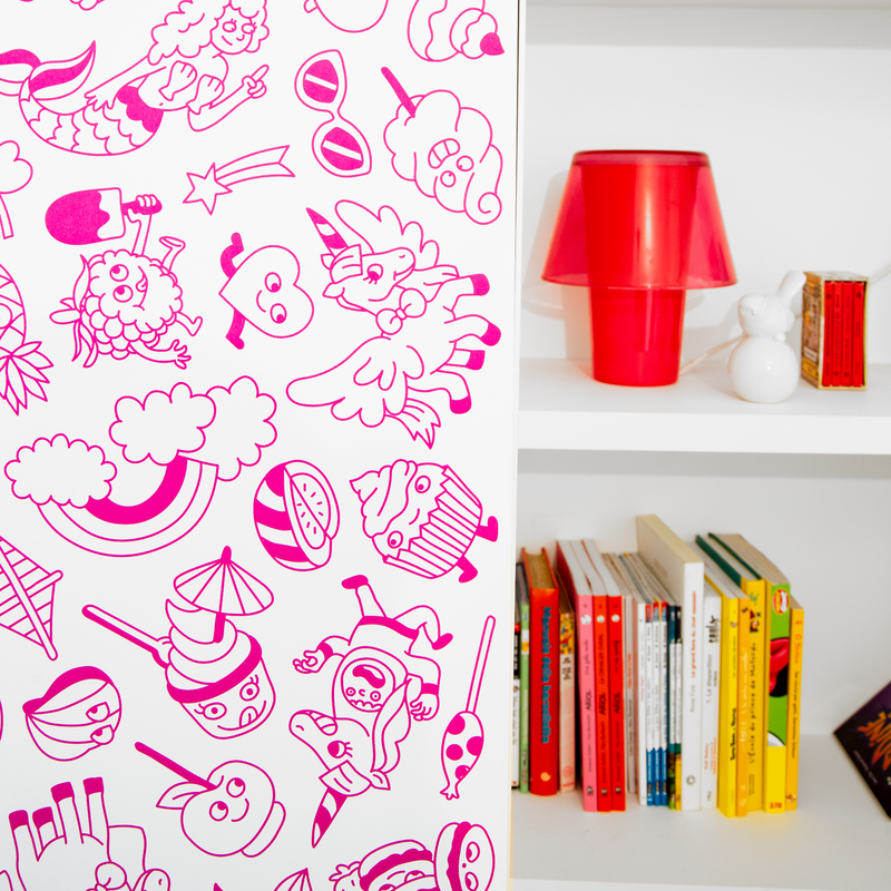 Décoration murale repositionnable OMY Stick-it Dreamland appliquée verticalement sur un meuble blanc, avec motifs arc-en-ciel, licornes et sucreries.