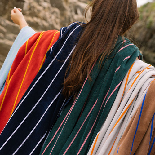 Persona vistiendo coloridas toallas de playa en un entorno natural.