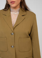 An'ge – Veste Zatalia Olive, blazer court kaki porté par un mannequin, avec un top en dentelle blanche