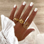 Instants Plaisirs – Bague Fei - Acier, main de femme avec des ongles blancs, portant trois bagues dorées