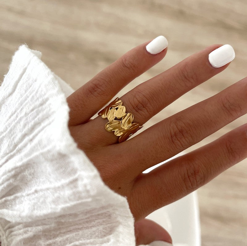 Instants Plaisirs – Bague Fei - Acier, bague dorée portée sur une main, vue de dessus, ongles blancs